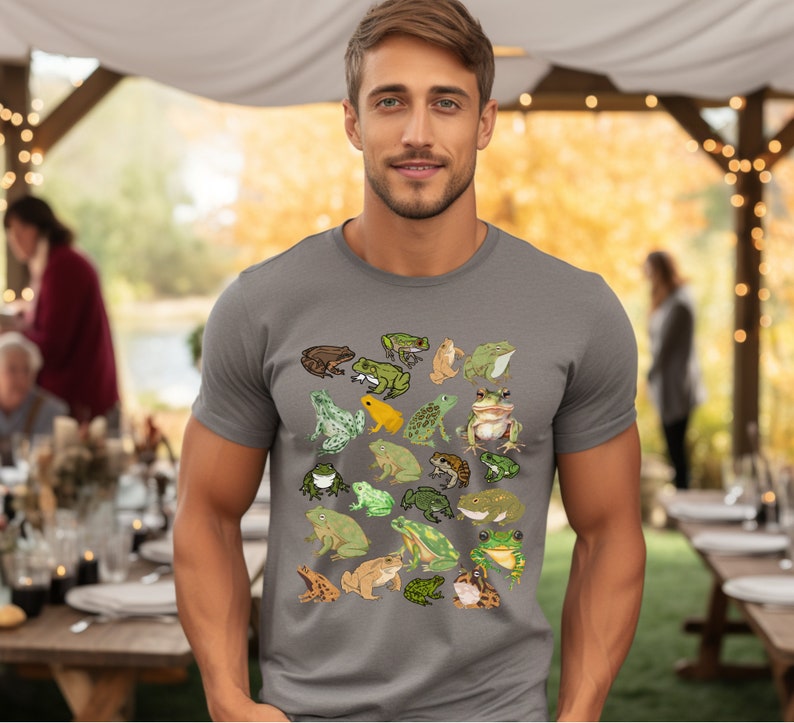 May include: A gray t-shirt with a pattern of various frogs in different colors and poses. The frogs are green, brown, yellow, and orange.