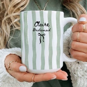 Striped pastel ceramic mug with black bow and custom text for bride, bridesmaid, or maid of honor; perfect as personalized bridal gift.