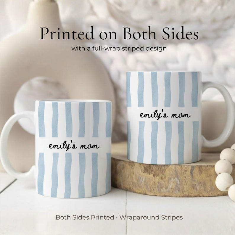 Puede incluir: Dos tazas de cer&aacute;mica blancas con rayas verticales azules y el texto "emily's mom" impreso. Las tazas tienen un dise&ntilde;o de rayas envolventes y est&aacute;n impresas por ambas caras. Las tazas est&aacute;n sobre una superficie de madera.