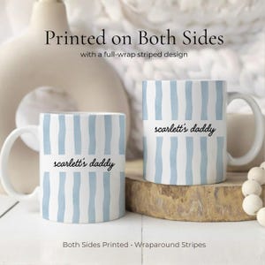 Puede incluir: Dos tazas de cer&aacute;mica blancas con rayas verticales azules y el texto "scarlett's daddy". Las tazas tienen un dise&ntilde;o de rayas envolventes y est&aacute;n impresas por ambas caras. Las tazas est&aacute;n sobre una superficie de madera.