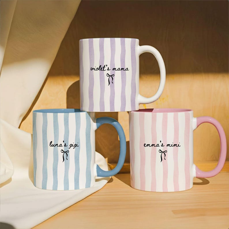 May include: Three ceramic mugs with vertical striped patterns in pastel colors. One mug is lavender and white, another is blue and white, and the third is pink and white. Each mug has a different name and bow graphic.