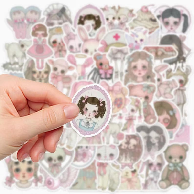 May include: A collection of pastel-colored stickers featuring illustrations of dolls, teddy bears, and other cute characters. A hand holds a sticker with a portrait of a girl with pigtails. The stickers have a vintage, whimsical aesthetic.