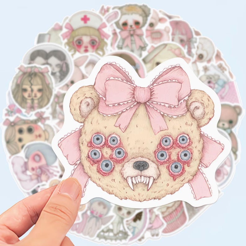 May include: A collection of stickers featuring a variety of eerie, pastel-colored illustrations. The central sticker is a beige teddy bear with multiple blue eyes, a pink bow, and sharp teeth. Other stickers include dolls and figures in pink and white.
