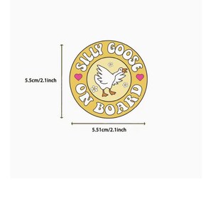 Op de afbeelding: Een ronde, gele sticker met de tekst "SILLY GOOSE ON BOARD". In het midden een illustratie van een witte gans, omringd door kleine bloemen en roze hartjes. De sticker heeft een diameter van 5,5 cm. Een leuk, retro-achtig ontwerp.