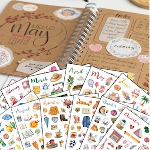 Peut inclure: Un journal à spirales avec le mot "May" et une page de calendrier. Une collection d'autocollants mensuels avec des illustrations à l'aquarelle d'objets saisonniers comme des chapeaux, des fleurs et des parapluies. Le journal contient aussi des notes et des idées.