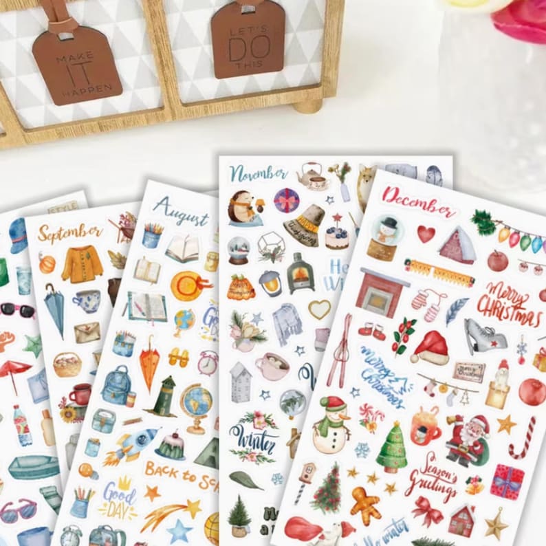 May include: A collection of decorative sticker sheets featuring various seasonal themes. The sheets are labeled with months like September, August, November, and December. Each sheet is filled with colorful illustrations of related objects and text.