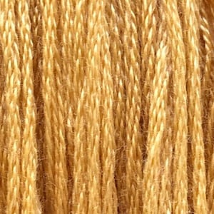 May include: Close-up of a spool of golden-yellow yarn. The yarn is tightly wound, showing a textured surface with visible strands. The color is a warm, natural tone, suggesting a fiber craft material.