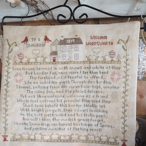 May include: A framed cross-stitch sampler featuring a poem by William Wordsworth, titled "To a Snowdrop." The design includes a house, birds, and floral elements, with the year 1819. The text is in dark brown thread on a beige fabric.
