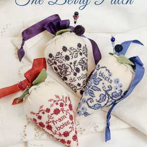 May include: Three embroidered fabric strawberries, each with a different design and color scheme. The strawberries are labeled "fraise", "blue", and "de mûre". The image is titled "The Berry Patch" and is by Erica Michaels Needleart Designs.