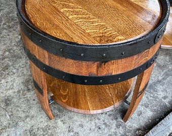 May include: A wooden barrel end table with a black metal band and a lower shelf. The table has a natural wood finish and is made from reclaimed wood.