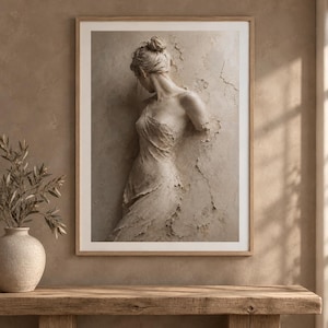 Puede incluir: Una lámina de arte mural enmarcada que muestra una escultura en relieve de color beige monocromático de una figura con el pelo recogido, envuelta en tela texturizada que se funde con una pared agrietada y desgastada, en un marco de madera clara.