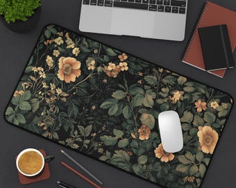 Puede incluir: Un tapete de ratón negro y verde con estampado floral y un ratón de ordenador blanco en la parte superior. El tapete de ratón está rodeado por un ordenador portátil, una taza de café, lápices y una libreta.