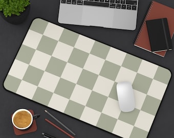 Pode incluir: Um tapete de mesa xadrez verde e branco com um rato de computador branco em cima. O tapete está sobre uma superfície preta com um laptop, uma planta em vaso e uma chávena de café.