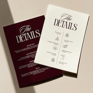 Könnte beinhalten: Zwei Hochzeitsdetailkarten. Eine ist weinrot, die andere cremefarben. Beide Karten tragen die Worte "The DETAILS" in einer dekorativen Schriftart. Die cremefarbene Karte listet den Hochzeitsplan auf, einschließlich der Zeremonie- und Empfangszeiten.
