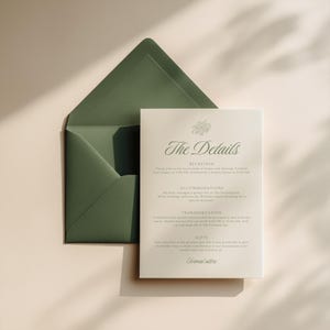 Front-facing wedding information card resting over a deep sage green envelope, showcasing elegant serif fonts and floral emblem, with clear sections for reception, accommodations, transportation, and gift notes.