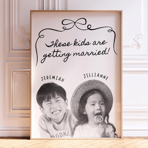 Könnte beinhalten: Ein rechteckiger gerahmter Druck mit einem Schwarz-Weiß-Foto von zwei Kindern, Jeremiah und Jillianne. Darüber steht der Text "These kids are getting married!" in schwarzer Schreibschrift, eingerahmt von einer dekorativen Strichzeichnung einer Schleife.