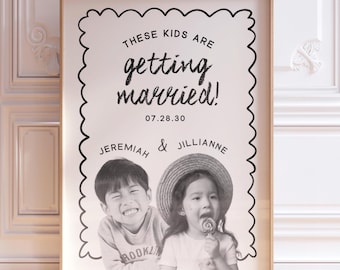 May include: A framed vertical poster with a scalloped black border on a white background. The text reads: THESE KIDS ARE getting married! 07.28.30 JEREMIAH & JILLIANNE. Below the text is a black and white photograph of two children smiling.
