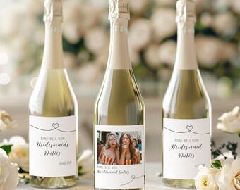 May include: Three champagne bottles with personalized labels that say "Pairs well with Bridesmaid Duties". The labels have a heart and a photo of two women.