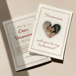 Peut inclure: Deux cartes rectangulaires blanches avec une bordure rouge festonnée. L'une présente le texte "Veronica, will you be my bridesmaid?" et une photo en forme de cœur de deux personnes. L'autre affiche "Dear Veronica" et un message se terminant par "xoxo, julia."