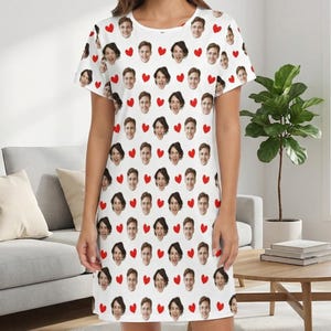 May include: White nightdress with a repeating pattern of faces and red hearts. The nightdress has a round neck and falls to the mid-thigh. The faces appear to be of different people.