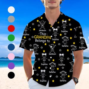 May include: Black button-up shirt with a repeating pattern of stick figures, stars, and the text "This GRANDPA Belongs to" with names. The shirt has a classic collar and short sleeves. The background is a beach scene.