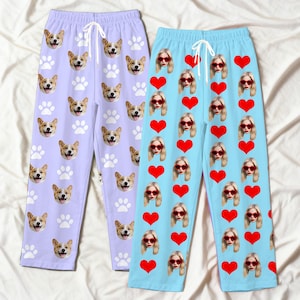 May include: Two pairs of pajama trousers. One pair is light purple with a pattern of corgi faces and white paw prints. The other pair is light blue with a pattern of red hearts and faces wearing red sunglasses.