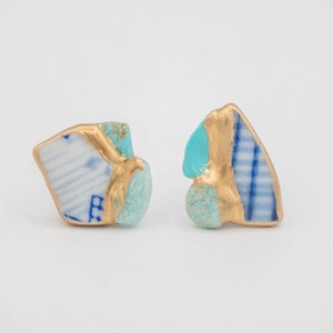 May include: A pair of small, asymmetrical earrings made from repurposed porcelain and turquoise. The earrings are gold-plated and have a blue and white pattern.