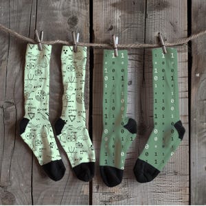 May include: Four pairs of knee-high socks with different patterns. Two pairs feature a green background with black mathematical equations and symbols. The other two pairs have a green background with black 1s and 0s.
