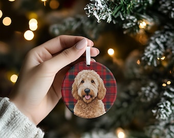 May include: A round ceramic Christmas ornament featuring a brown and white doodle dog with a red and black plaid background.