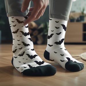 May include: A pair of white socks with a black bat pattern. The socks are shown on a person's feet.