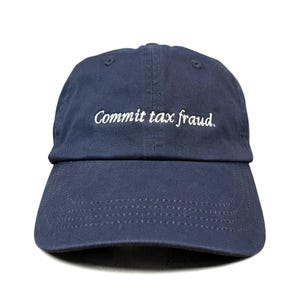 Puede incluir: Una gorra de béisbol azul marino con el texto bordado en blanco "Commit tax fraud." en el panel frontal. La gorra tiene una visera curva con costuras visibles y una corona estructurada con ojales para la ventilación.