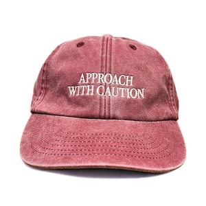 Gorra de béisbol de perfil bajo bordada con la frase "Acércate con precaución".
