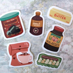 May include: A set of baking stickers featuring illustrations of ingredients like unsweetened cocoa powder, vanilla extract, molasses, butter, and eggs. The stickers are colorful and feature a hand-drawn style.