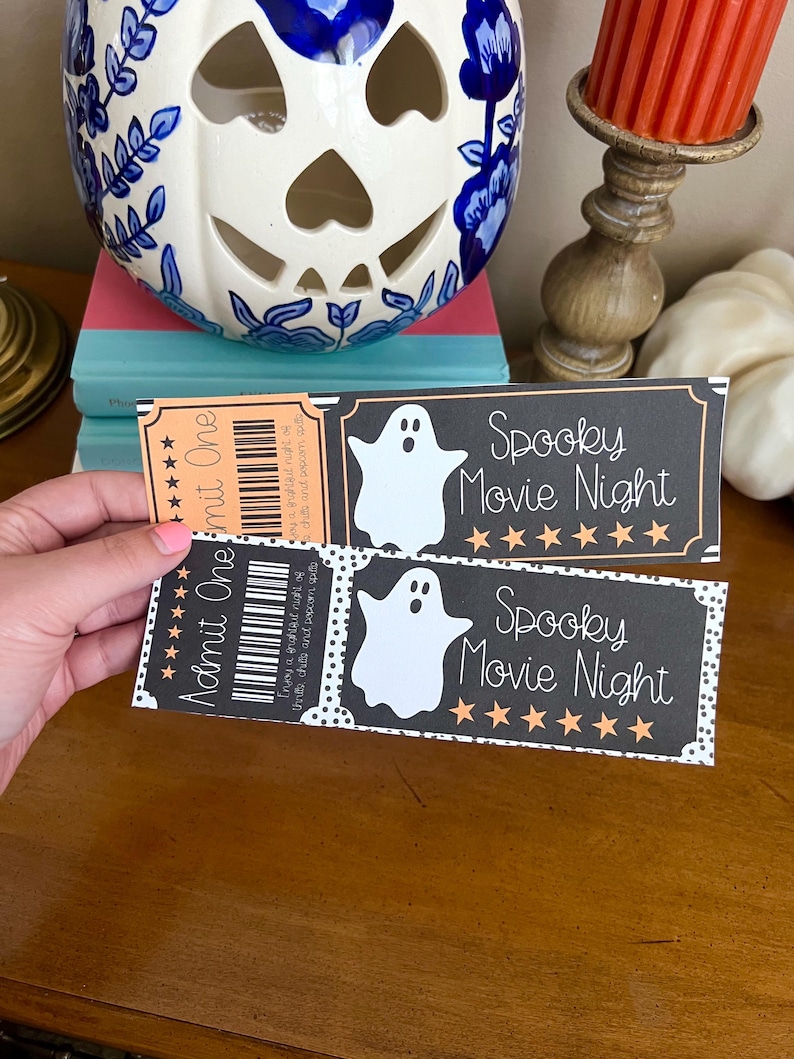 K&ouml;nnte beinhalten: Zwei schwarze und orangefarbene druckbare Halloween-Kinotickets mit einer Geistergrafik und dem Text "Spooky Movie Night" und f&uuml;nf goldenen Sternen.
