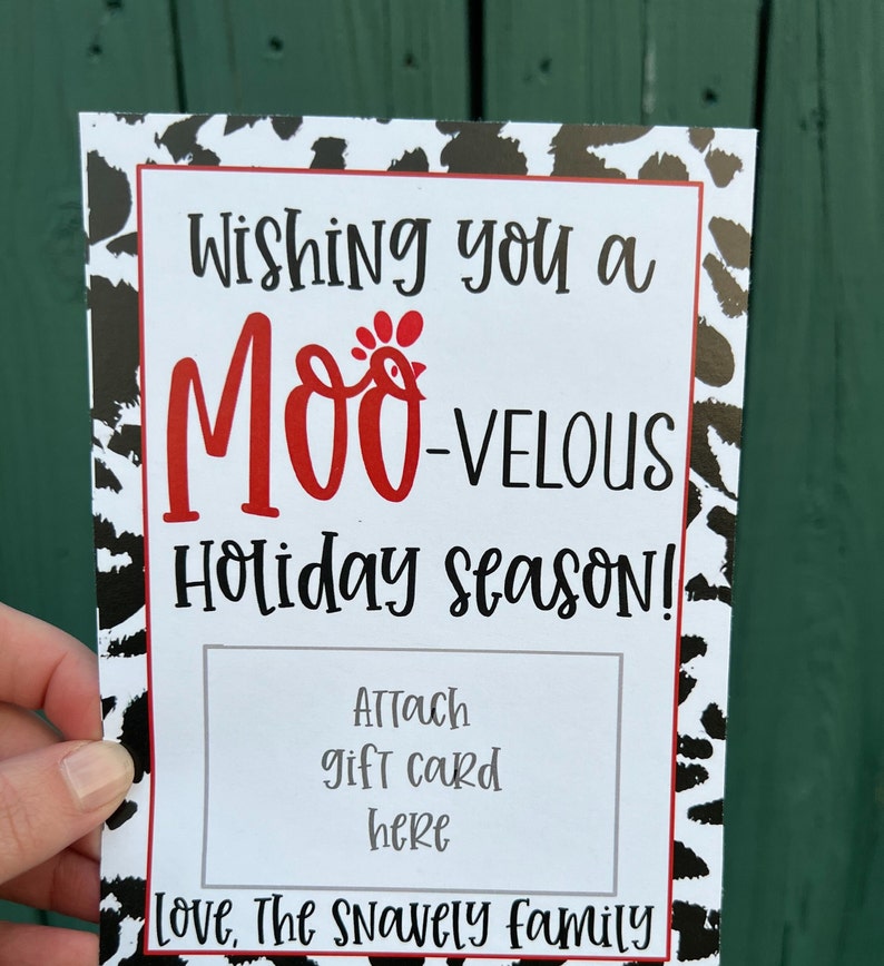 May include: A white card with black and white cow print border. The card says "Wishing you a MOO-VELOUS Holiday Season!" with a red chicken illustration. There is a white rectangle for attaching a gift card with the text "Attach gift card here". The card is signed "Love, The Snavely family".