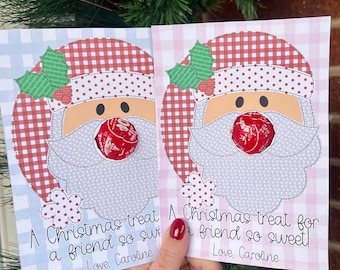 Puede incluir: Dos etiquetas de regalo de Navidad imprimibles con un Papá Noel de dibujos animados con un gorro a cuadros rojo y blanco y un caramelo rojo en la boca. El texto en las etiquetas dice "¡Un regalo de Navidad para un amigo tan dulce!" y "Con cariño, Caroline".