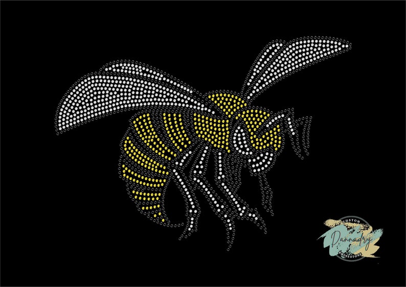 Puede incluir: Un dise&ntilde;o de abeja negro, blanco y dorado hecho de pedrer&iacute;a. La abeja est&aacute; en vuelo con las alas extendidas.