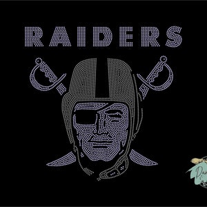 Puede incluir: Un dise&ntilde;o de strass en blanco y negro del logotipo de los Las Vegas Raiders. El logotipo presenta una calavera con un casco y espadas cruzadas detr&aacute;s. La palabra "RAIDERS" est&aacute; sobre la calavera.