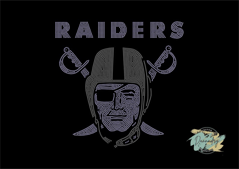 Puede incluir: Un dise&ntilde;o de strass en blanco y negro del logotipo de los Las Vegas Raiders. El logotipo presenta una calavera con un casco y espadas cruzadas detr&aacute;s. La palabra "RAIDERS" est&aacute; sobre la calavera.