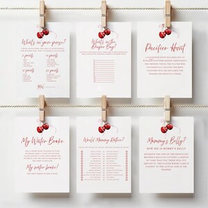 Op de afbeelding: Een set van tien printbare babyshower-spelkaarten met een kersenthema. De spellen omvatten "What's in your purse?", "What's in the diaper bag?", "Pacifier Hunt", "My Water Broke", "World Mommy Rather?" en "Mommy's Belly?"