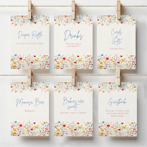 May include: Six printable signs with a floral border and blue text. The signs say "Diaper Raffle", "Drinks", "Cards & Gifts", "Mimosa Bar", "Babies are sweet...", and "Guestbook".