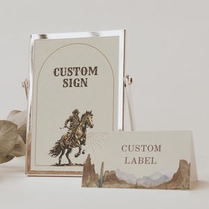 May include: A vertical rectangular sign in a metallic frame featuring the text CUSTOM SIGN and an illustration of a person riding a horse, paired with a horizontal rectangular label displaying the text CUSTOM LABEL and a desert landscape.