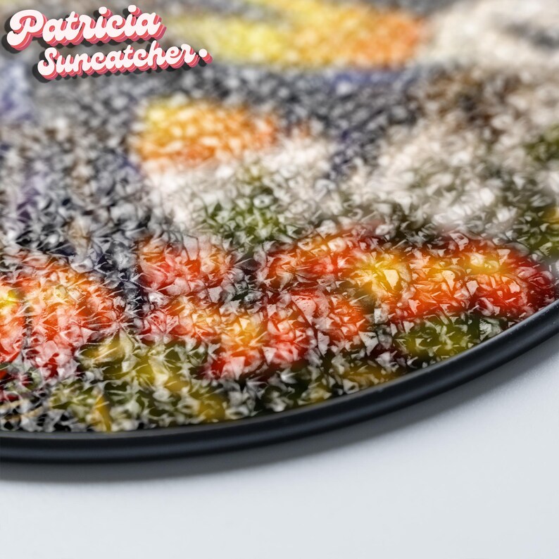 May include: A circular suncatcher featuring a textured, multifaceted surface with a vibrant mosaic of orange, yellow, green, and dark blue hues. The text 'Patricia Suncatcher' is printed in the upper left corner in a white and pink font.