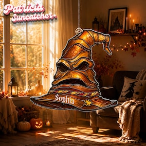 May include: A stained glass suncatcher shaped like a weathered, pointed wizard hat with deep amber and brown tones. The hat features a prominent, expressive face with a wide, open mouth and the name Sophia inscribed in white script on the brim.