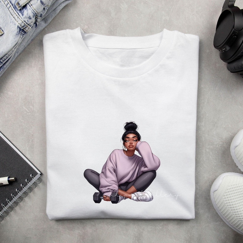 May include: White t-shirt featuring a seated illustration of a person in a lavender sweatshirt and gray leggings, holding a dumbbell. The person has dark hair in a bun and is wearing white sneakers. The illustration has a modern, artistic style.