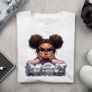 May include: A white t-shirt with a cartoon illustration of a young girl with brown skin and brown hair in two buns. She is wearing a pink shirt with a white pattern and is leaning on a dish rack full of dirty dishes. The girl has a frustrated expression on her face.