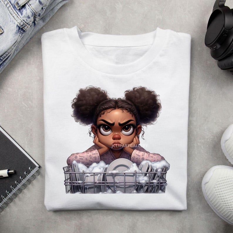 May include: A white t-shirt with a cartoon illustration of a young girl with brown skin and brown hair in two buns. She is wearing a pink shirt with a white pattern and is leaning on a dish rack full of dirty dishes. The girl has a frustrated expression on her face.