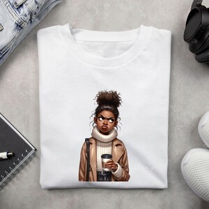Op de afbeelding: Een wit t-shirt met ronde hals voorzien van een grafische illustratie van een persoon met een hoog knotkapsel, gekleed in een beige coltrui en een lichtbruine jas, terwijl deze een donkere koffiebeker vasthoudt met een geconcentreerde blik.