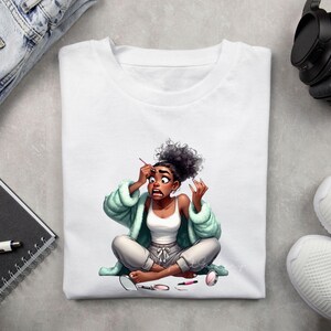 May include: White t-shirt featuring a cartoon illustration of a person applying makeup with a surprised expression. The person is wearing a white tank top, gray sweatpants, and a light green robe. Makeup items are scattered around.
