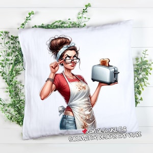 May include: White pillow with a cartoon illustration of a woman wearing glasses, a red shirt, and a white apron holding a toaster with toast. The woman has a stern expression. Text at the bottom reads "CAN ALSO USE FOR SUBLIMATION DESIGNS AND MORE."